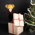 Pretty teen girl opening gift by Christmas tree