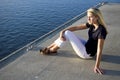 Pretty teen girl sitting on dock by water watching Royalty Free Stock Photo