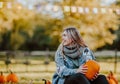 Pretty teen girl sitting on a pumpkin`s field holding a pumpkin and smile Royalty Free Stock Photo