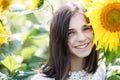 Pretty teen girl standing in a field near beautiful sunflower. The girl is genuinely smiling Royalty Free Stock Photo