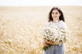 Pretty teen girl standing in a field among wheat. Girl holding a large bouquet of flowers in her hands Royalty Free Stock Photo