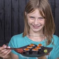 Pretty teen girl with sushi roll , teenage girl eating japanese sushi