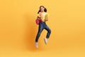 Pretty teen girl going to school, jumping on yellow background Royalty Free Stock Photo