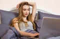 Pretty teen woman using her laptop in bed. Beautiful girl in glasses working on laptop in bedroom Royalty Free Stock Photo