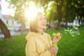 Pretty teenage girl blowing soap bubbles on a sunset. Child having fun in a park in summer Royalty Free Stock Photo