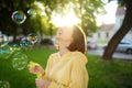 Pretty teenage girl blowing soap bubbles on a sunset. Child having fun in a park in summer Royalty Free Stock Photo