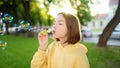 Pretty teenage girl blowing soap bubbles on a sunset. Child having fun in a park in summer Royalty Free Stock Photo