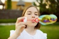 Pretty teenage girl blowing soap bubbles on a sunset. Child having fun in a park in summer Royalty Free Stock Photo