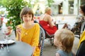 Pretty teenage girl eating tasty fresh ice cream outdoors on sunny summer day. Big sister feeding a dessert to her toddler brother Royalty Free Stock Photo