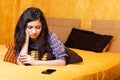 Pretty teenage girl lying in bed an looking at her phone with sa Royalty Free Stock Photo