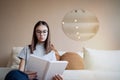 Teenage girl reading book at home while sitting on sofa Royalty Free Stock Photo