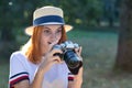 Pretty teenage girl with red hair looking amazed in photo camera in summer park Royalty Free Stock Photo