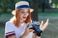 Pretty teenage girl with red hair looking amazed in photo camera in summer park Royalty Free Stock Photo