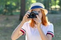 Pretty teenage girl with red hair taking picture with photo camera in summer park Royalty Free Stock Photo