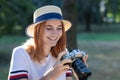 Pretty teenage girl with red hair taking picture with photo camera in summer park Royalty Free Stock Photo