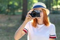 Pretty teenage girl with red hair taking picture with photo camera in summer park Royalty Free Stock Photo