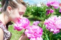 Pretty teenage girl smelling pink blossoming peony flowers in pa Royalty Free Stock Photo