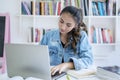 Pretty teenage girl studying with laptop in library Royalty Free Stock Photo