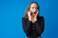 Pretty teenage girl talking on the mobile phone against blue background Royalty Free Stock Photo