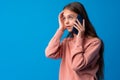 Pretty teenage girl talking on the mobile phone against blue background Royalty Free Stock Photo