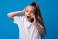 Pretty teenage girl talking on the mobile phone against blue background Royalty Free Stock Photo