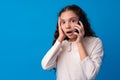 Pretty teenage girl talking on the mobile phone against blue background Royalty Free Stock Photo