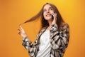 Pretty teenage girl talking on the mobile phone against yellow background Royalty Free Stock Photo