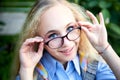Pretty teenage girl 14-16 year old with curly long blonde hair and in glasses in the green park in a summer day outdoors. Royalty Free Stock Photo