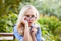 Pretty teenage girl 14-16 year old with curly long blonde hair and in glasses in the green park in a summer day outdoors. Royalty Free Stock Photo