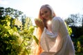 Pretty teenage girl 14-16 year old with curly long blonde hair in the green park with white flower in a summer day outdoors and Royalty Free Stock Photo