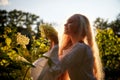 Pretty teenage girl 14-16 year old with curly long blonde hair in the green park with white flower in a summer day outdoors and Royalty Free Stock Photo