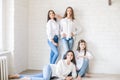 Pretty teenage girls models in trendy jeans and white shirts in the studio against the background of a white brick wall. Royalty Free Stock Photo