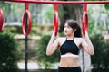 Pretty teenage woman in black workout clothes. People are doing outdoor exercise in a park. Person play with red trapeze players. Royalty Free Stock Photo