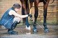 Pretty teenage young girl equestrian washing hoofs and legs Royalty Free Stock Photo