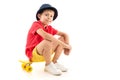 Pretty teenager boy in red t-shirt, jacket sits with yellow penny,  on white background Royalty Free Stock Photo