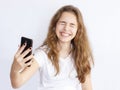 Pretty teenager girl with long hair makes selfie with funny laughing face