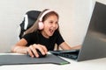 A gamer girl in pink headphones screams while playing on a laptop. Pretty teenager playing computer game at home late Royalty Free Stock Photo