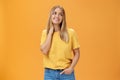 Pretty and tender cute european female independent freelancer in yellow t-shirt sighing touching neck and gazing dreamy