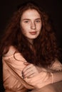 Pretty tender redhead girl with crossed arms posing in beige blouse