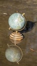 Pretty terrestrial globe in wood and metal, placed in a puddle outside, and its reflection