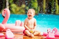 Baby sitting on the edge of the pool and smiling with pink flamingo lifebuoy Royalty Free Stock Photo