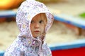 Pretty toddler girl wearing rain jacket looking from the hood on the playground