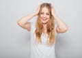 Pretty toothy laughing young woman with fair blond long hair in casual dress holding the head the hands. Studio shot of good Royalty Free Stock Photo