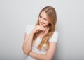 Pretty toothy laughing young woman with fair blond long hair in casual dress holding the head the hands. Studio shot of good Royalty Free Stock Photo