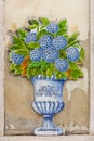 Pretty traditional antique tile wall ornament representing a vase filled with a hydrangea bouquet in blue and green