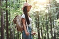 Pretty traveling woman with backpack and hat standing in forest