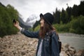 Pretty traveling woman standing on top of mountain at sunset and using mobile phone