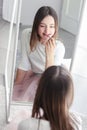 Pretty tween girl rouge lips holding red lipstick looking at big mirror Royalty Free Stock Photo