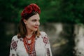 Pretty ukrainian woman in traditional embroidery vyshyvanka dress and red flowers wreath near river. Ukraine freedom Royalty Free Stock Photo