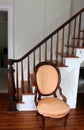 Pretty upholstered wood chair set next to staircase, inviting someone to sit a few minutes